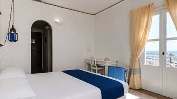 Habitación de hotel con cama, escritorio, silla, lámpara y ventana.