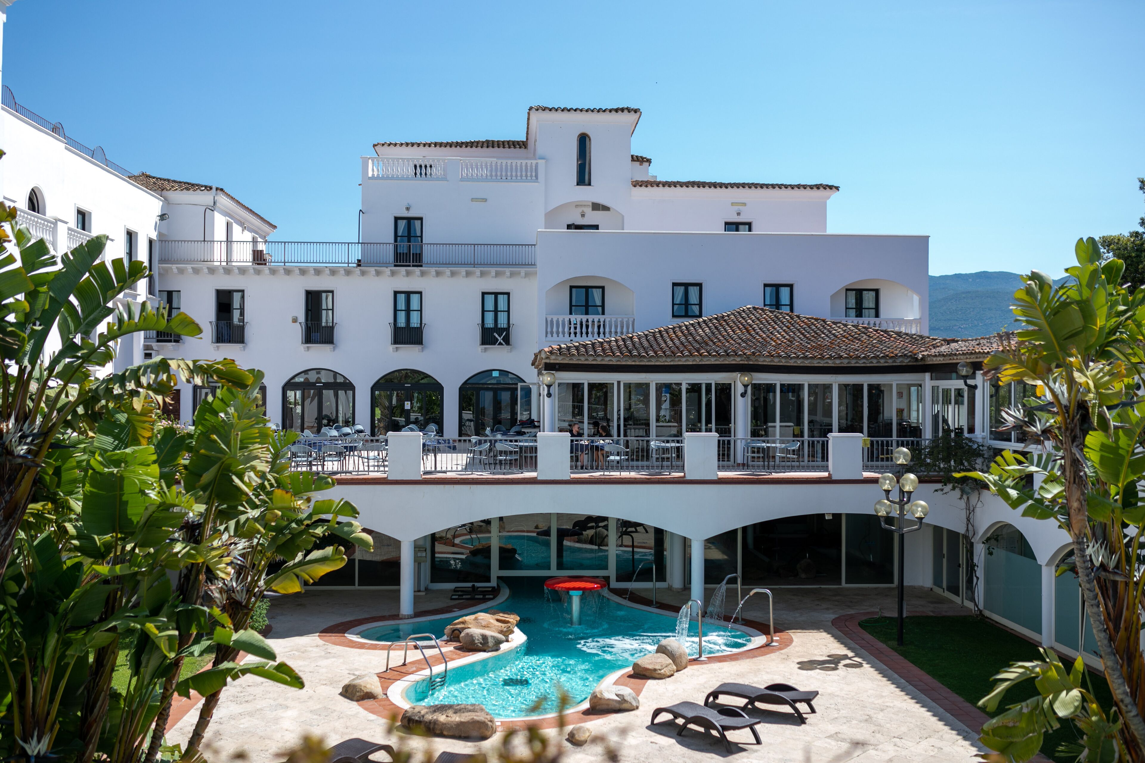 A hotel with a pool area, outdoor seating, and a view of the mountains.