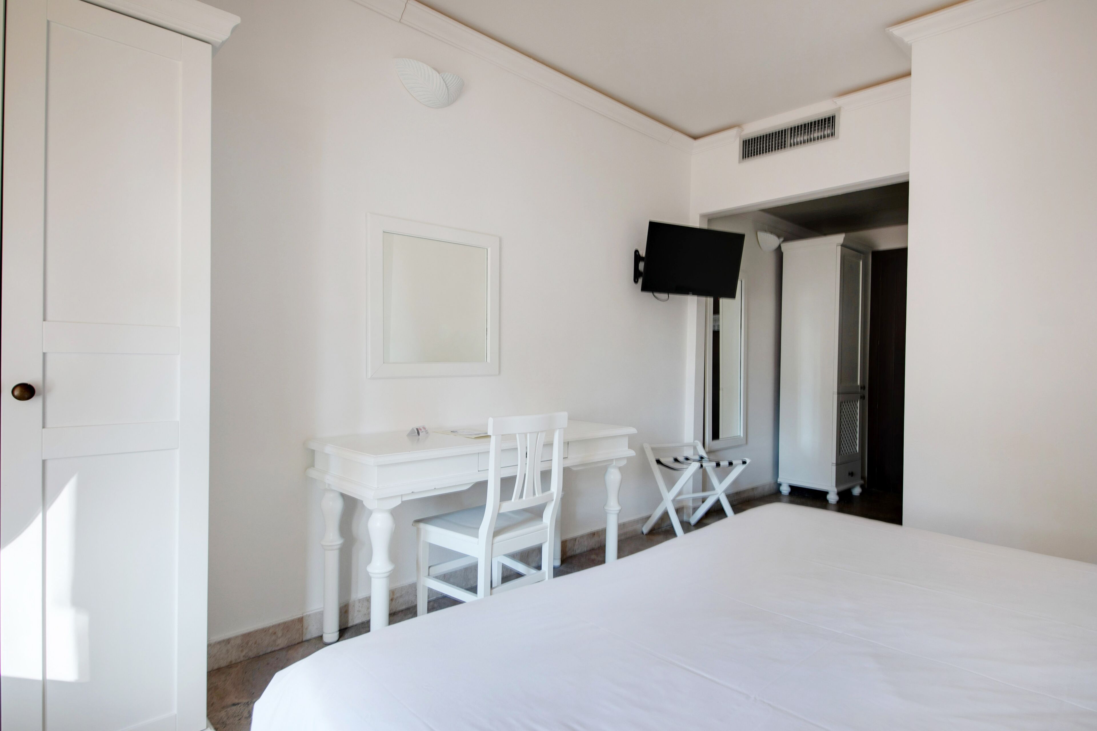 Un dormitorio con cama, escritorio, silla, televisor y armario.