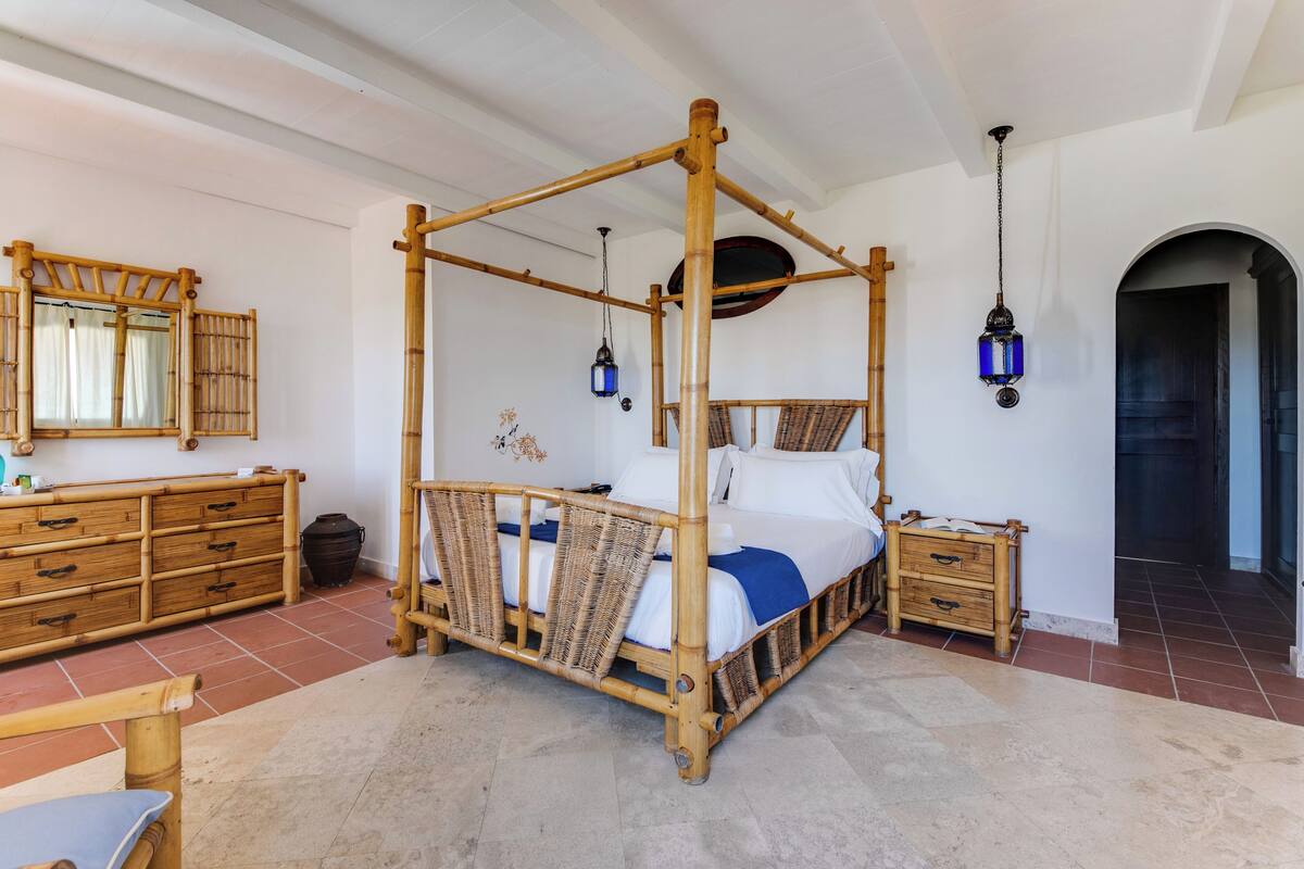 Ein Himmelsbett mit Holzrahmen, ein Nachttisch, ein Spiegel und eine Pendelleuchte.