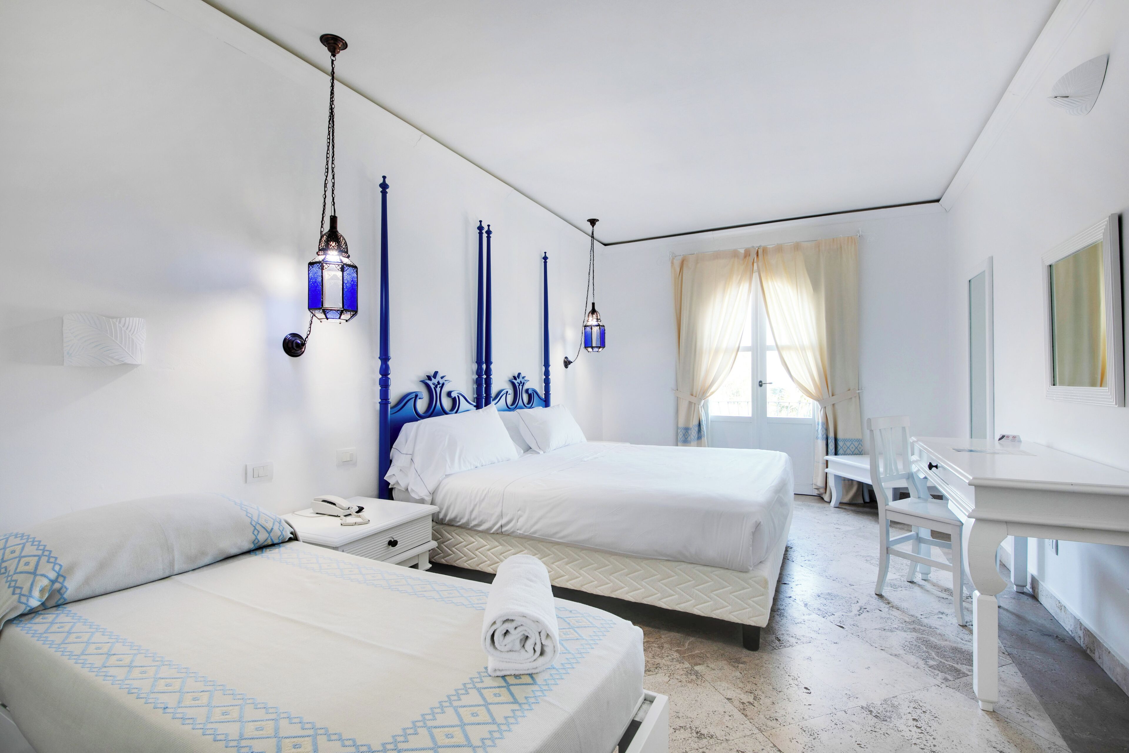 Hotellihuone, jossa on kaksi sänkyä, työpöytä ja tuoli.