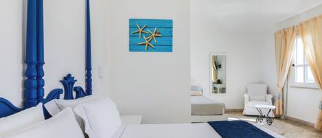Habitación de hotel con una cama grande, una silla, una mesita y una obra de arte azul en la pared.
