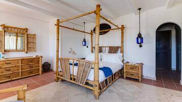 Una cama con dosel de madera, una mesita de noche, un espejo y una lámpara colgante.