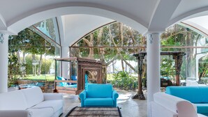 Amplio espacio interior con sofás blancos, un sillón azul y una estructura de madera.