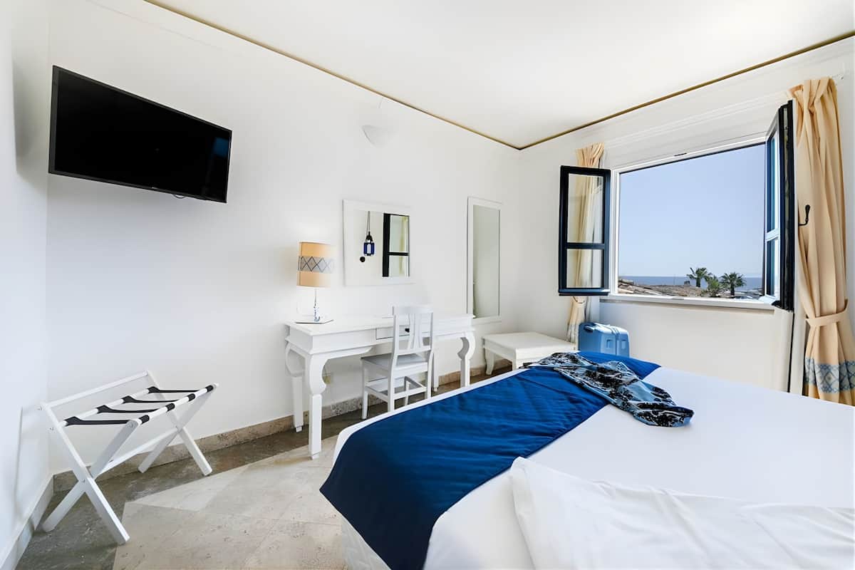Ein Hotelzimmer mit Bett, Schreibtisch, Stuhl, Fernseher und einem Fenster mit Blick.