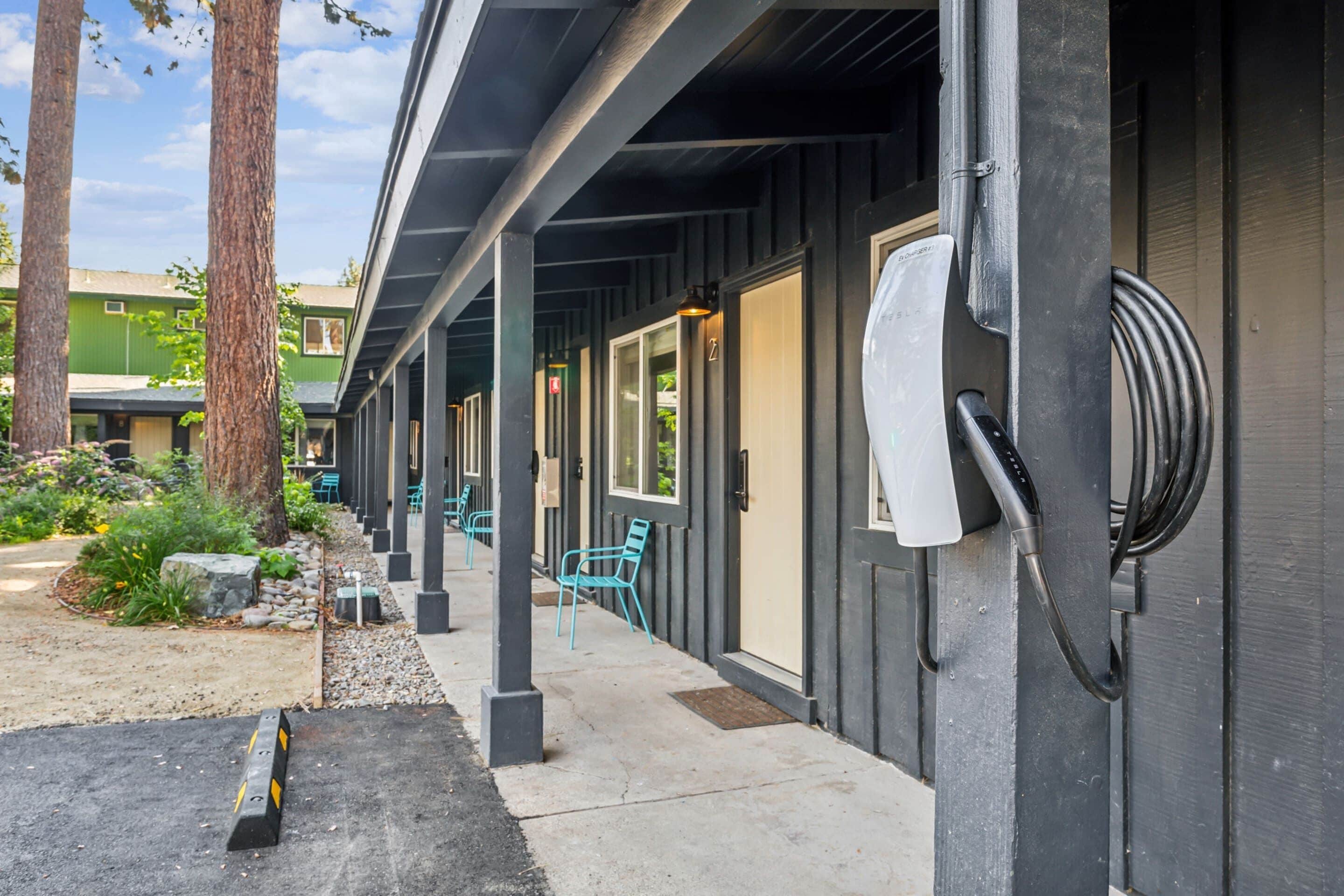 A row of outdoor seating with a covered area, a power outlet, and a building with a dark facade.