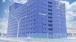 Un moderno edificio azul con un diseño angular singular, identificado como Montempo Apartment Hotel.