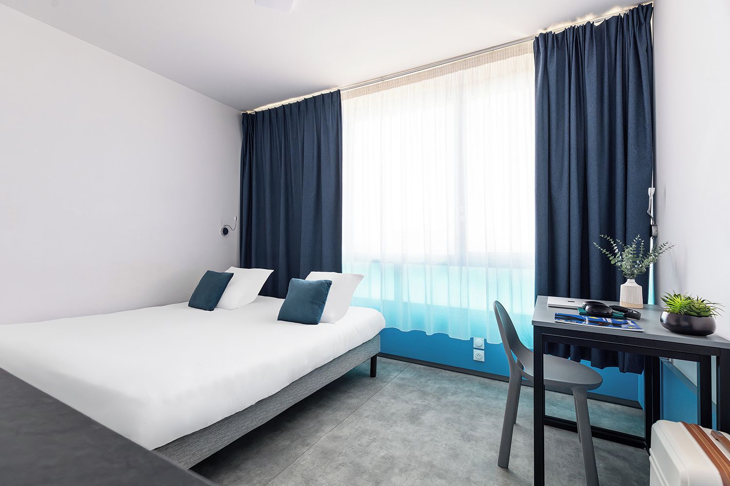 Una habitación de hotel con una cama, un escritorio y una silla.