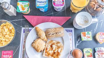 Mesa de café da manhã com croissants, cereais e diversos produtos lácteos.