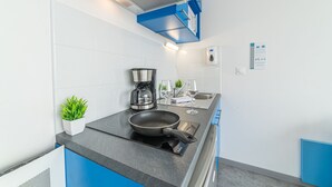 Una cocina moderna con estufa integrada, cafetera y una pequeña planta en maceta.