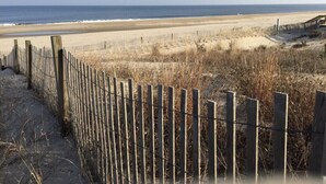 Een strand met een houten omheining en een helder uitzicht op de oceaan.