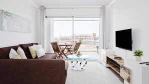 Un salon moderne avec un canapé marron, une table basse en verre et un téléviseur à écran plat.
