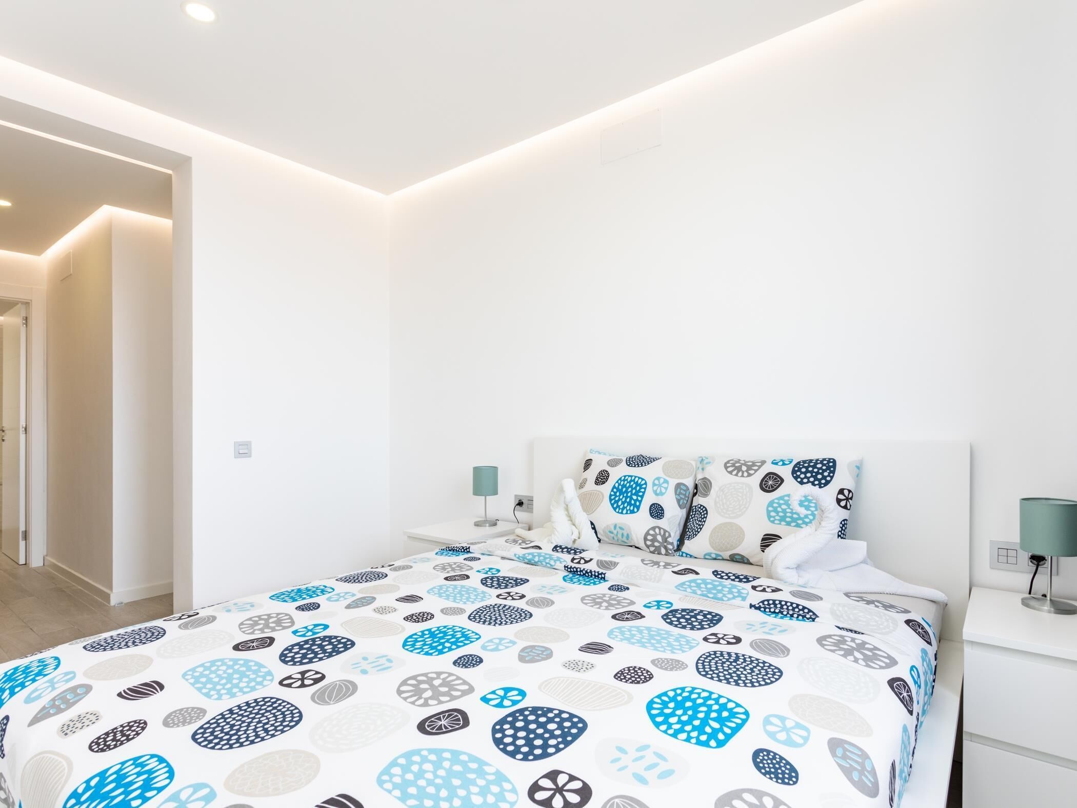 A modern bedroom with a bed, bedside tables, and a nightstand.