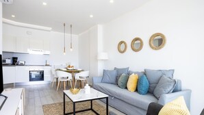 A modern living room with a grey sofa, a coffee table, and a dining area with a white table and chairs. - Beautiful ground floor with terrace and partial sea view in Costa Adeje (Adeje)