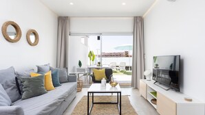 A modern living room with a grey sofa, a coffee table, and a TV on a stand. - Beautiful ground floor with terrace and partial sea view in Costa Adeje (Adeje)