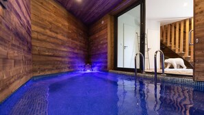 An indoor swimming pool with wooden walls and a glass door leading to a room with a polar bear statue. - Chalet with spa/heated pool, lake view, ski-in/ski-out access, fire pit, 5-star rating (Les Angles)