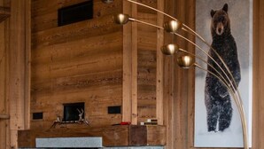 A cozy cabin interior with a stone fireplace, wooden walls, a bear painting, and a modern lamp. - Chalet with spa/heated pool, lake view, ski-in/ski-out access, fire pit, 5-star rating (Les Angles)