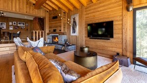 A log cabin interior with a fireplace, a sofa, a TV, and a dining area. - Chalet with spa/heated pool, lake view, ski-in/ski-out access, fire pit, 5-star rating (Les Angles)