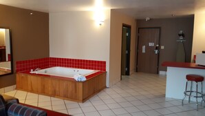 Un baño con una bañera de madera, paredes de azulejos rojos, un lavabo blanco y un espejo.