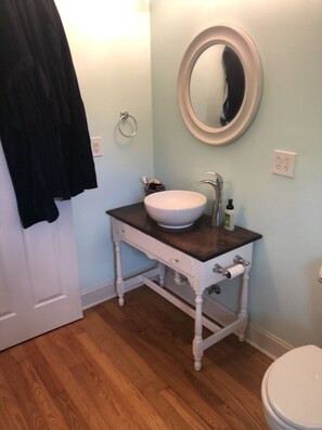 A bathroom with a white sink, dark countertop, and a round mirror. - Isolate Stay at Pilot Mountain (Pinnacle)