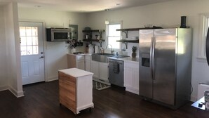 Een moderne keuken met witte kasten, roestvrijstalen apparatuur en een houten kledingkast.
