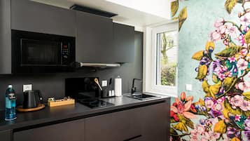 A modern kitchen with a microwave, stove, and sink, and a window with a view of greenery.