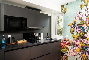 Una cocina moderna con microondas, estufa y lavamanos, y una ventana con vistas a zonas verdes.