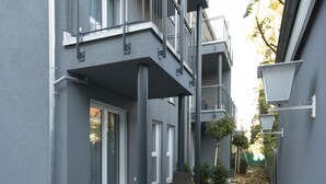 Un bâtiment moderne doté d’un étroit passage, de balcons et d’un petit espace jardin.