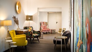 Un salon moderne avec un fauteuil jaune, un fauteuil à motifs, une table ronde et une lampe.
