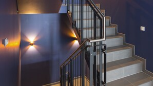 Un escalier moderne avec des rampes en métal et des appliques murales éclairées.