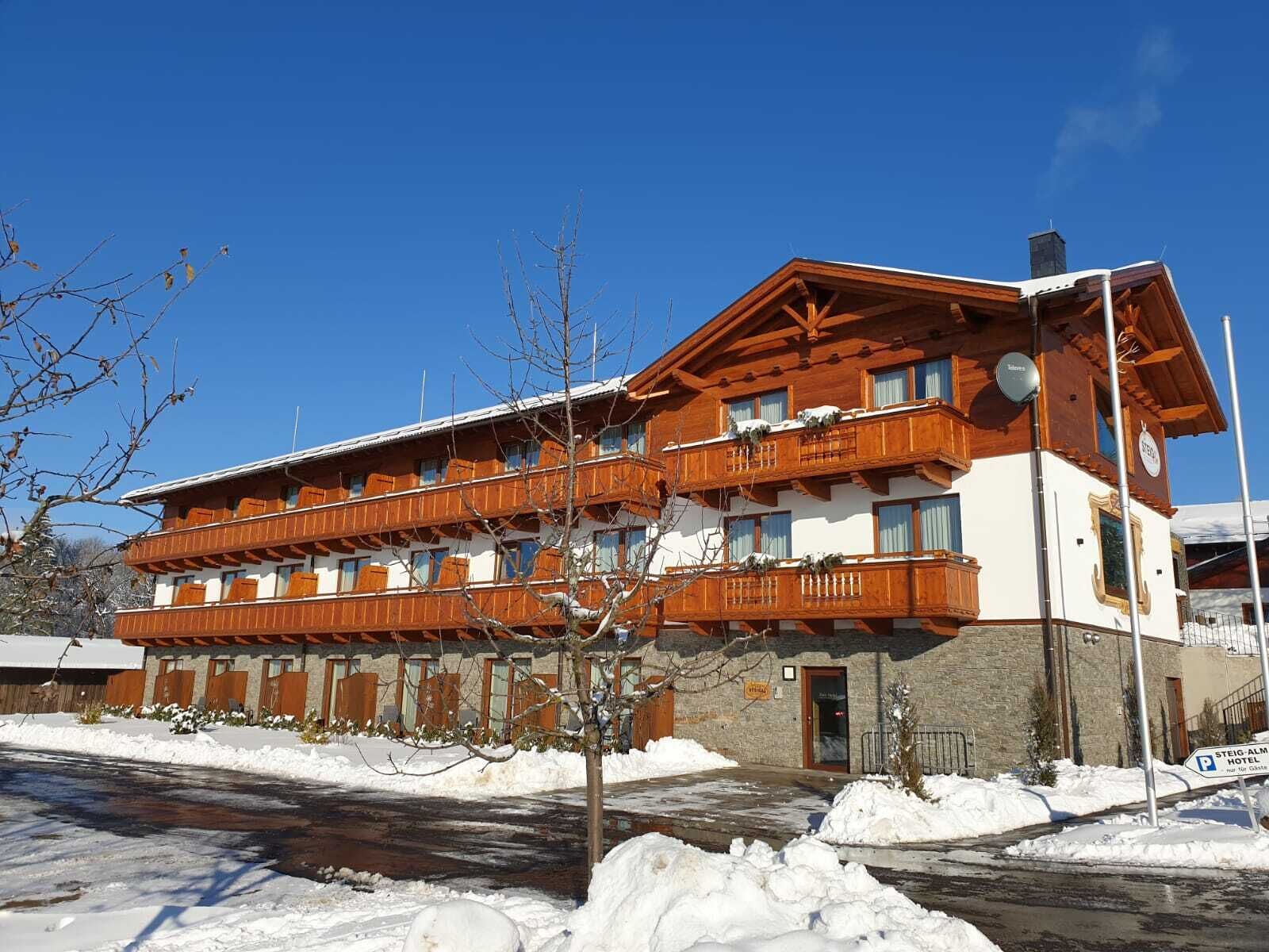 Een hotel met meerdere verdiepingen, houten balkons en een stenen gevel.