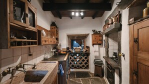 Cozinha estreita com armários de madeira, piso de pedra e uma pequena janela.