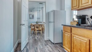 Una cocina con armarios de madera, un refrigerador blanco y una zona de comedor con mesa y sillas.