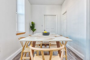 A dining area with a white table and chairs, a small plant, and a door in the background. - Stairway | 3BR Apt w W/D Ideal for Groups (Philadelphia)