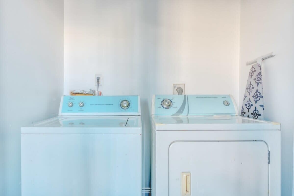 Twee witte wasmachines in een wasserij met een handdoekhouder aan de muur.