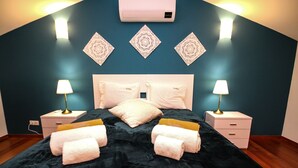 A bedroom with a black bedspread, two white pillows, a white headboard, and two bedside tables with lamps. - LUXURY APARTMENT - T1 pool view - PRAIA DA LUZ (Luz)