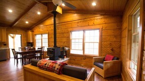 A cozy cabin interior with a wooden dining area, a sofa, and a fireplace. - Old World Craftmanship with Modern Amenities (Bristol)