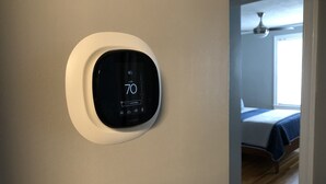 A thermostat mounted on a wall displaying a temperature of 70 degrees.