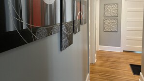 A hallway with abstract wall art, a wooden floor, and a white door.