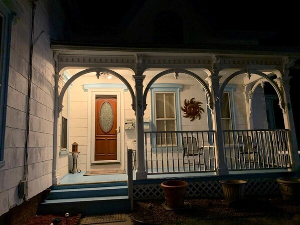 A porch with a wooden door, a small table, and potted plants.