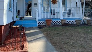 Una casa blanca amb un porxo blau, una xemeneia i una decoració de sol.