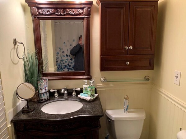 Un baño con tocador, lavabo, espejo e inodoro.