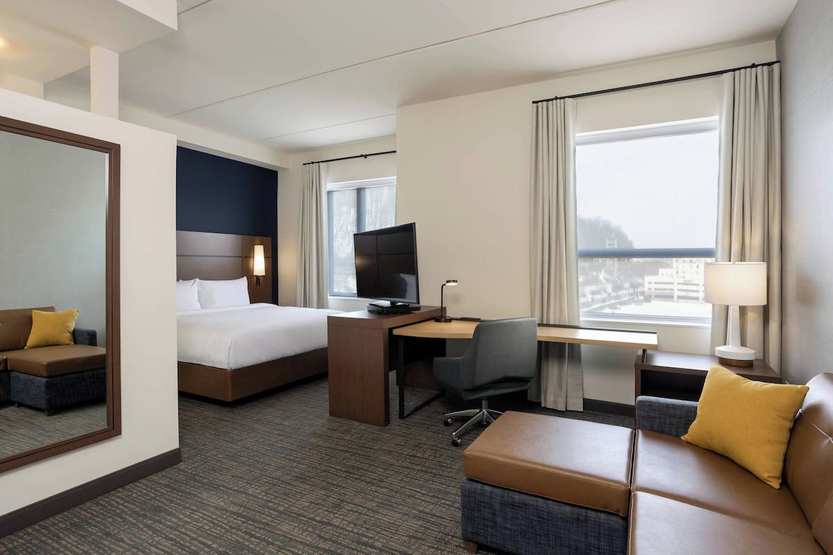 A hotel room with a bed, desk, computer, and seating area.