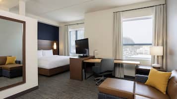 Quarto de hotel com cama, escrivaninha, computador e área de estar.