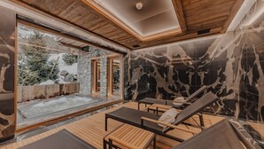 Een spa-ruimte met houten vloeren, een whirlpool en loungestoelen.