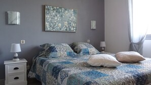 Ein Schlafzimmer mit einem Bett, zwei Nachttischen, einem Wandbild und einer Ablagefläche.