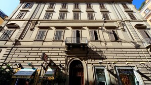 Un bâtiment historique doté d’une entrée centrale, de nombreuses fenêtres et d’un balcon.