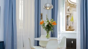 Un coin repas avec une table ronde, des chaises blanches, un vase avec des fleurs et un luminaire suspendu.