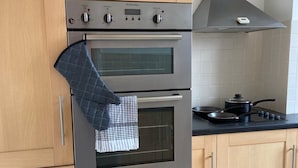 A kitchen with wooden cabinets, a stainless steel oven, a black stovetop, and a range hood. - Central Location - 2 Bedroom Apartment (Reading)