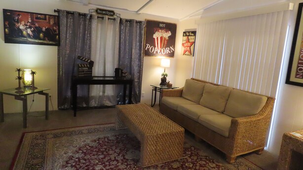 Un salon avec un canapé, une table basse, une lampe, un téléviseur et une affiche accrochée au mur.